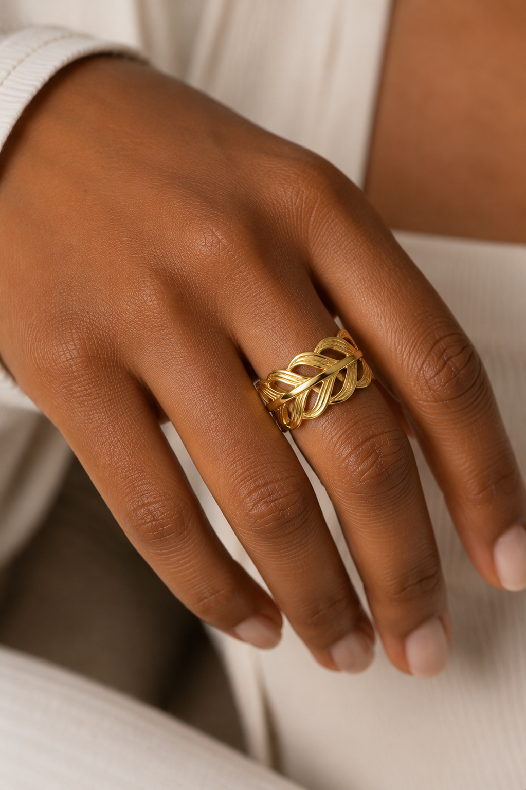Gold leaf ring on a person's finger with a neutral background