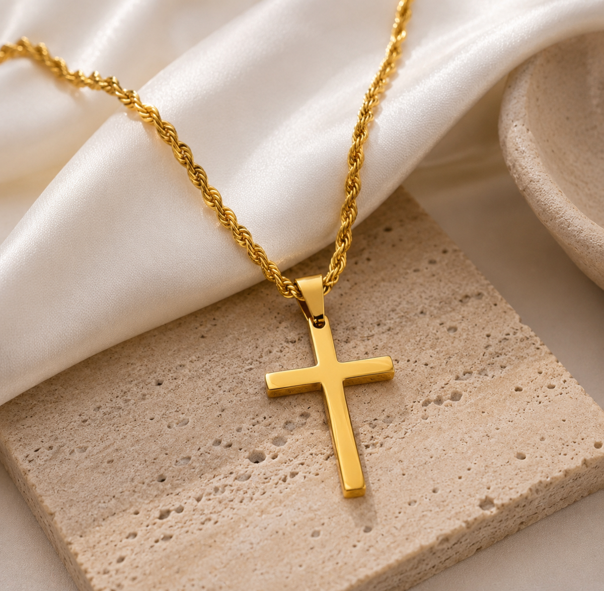 Gold cross necklace on a textured surface with a white fabric background