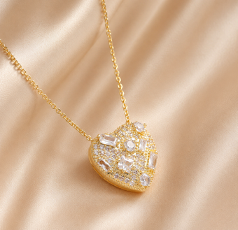Gold necklace with a heart-shaped pendant on a beige fabric background