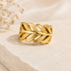 Gold ring with braided design on a beige stone surface